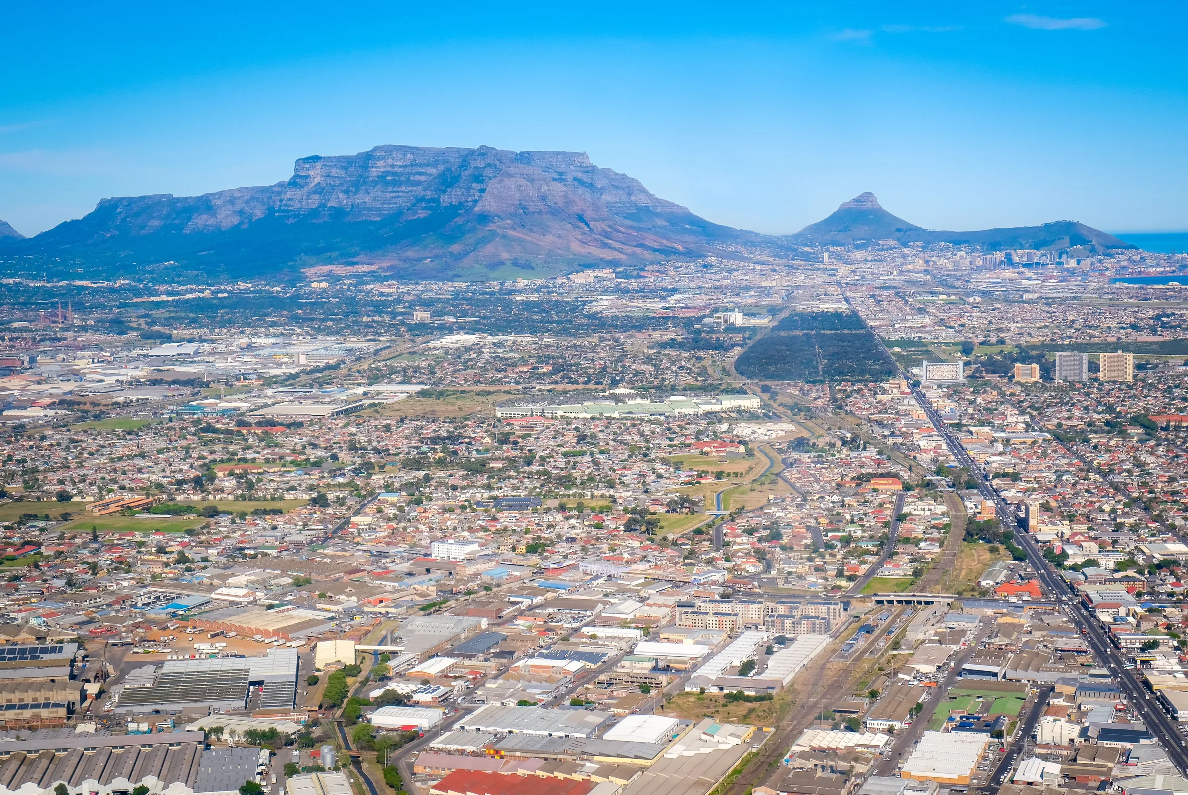 Table Mountain, Devil's Peak and Lion's Head above Cape Town's suburbs and industrial areas, seen from the air
