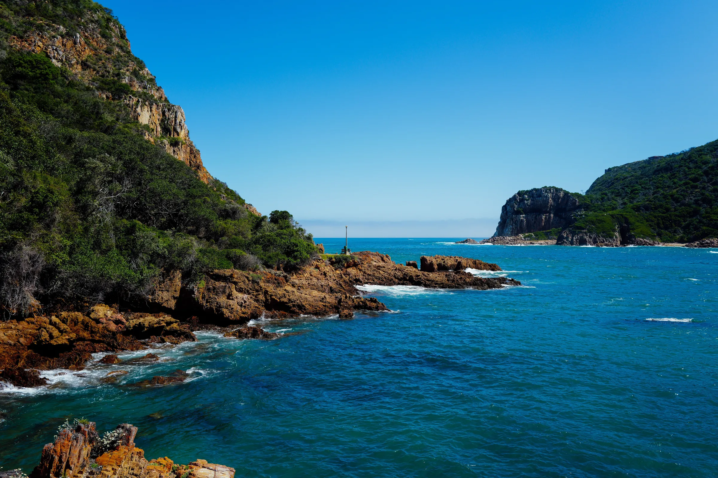 Cliffs and a rocky headland above a deep blue bay