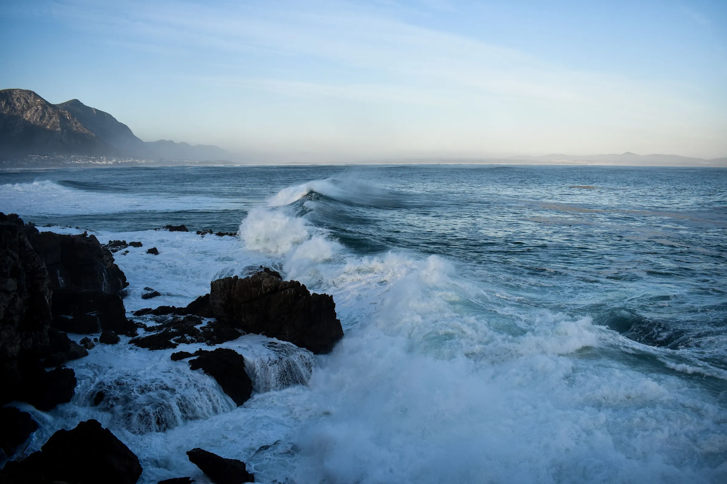 Waves breaking over dark rocks on a rugged shore