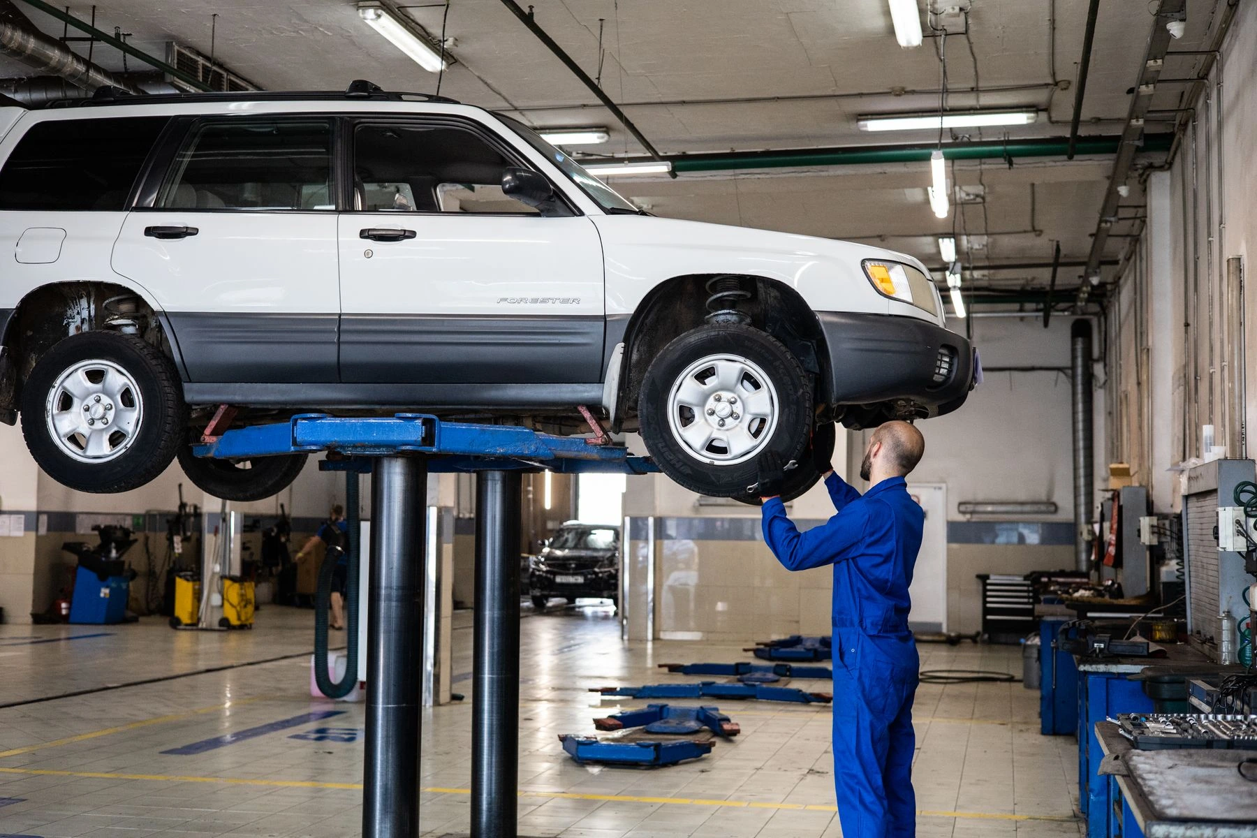 Mechanic inspecting the underside of a vehicle on a workshop lift