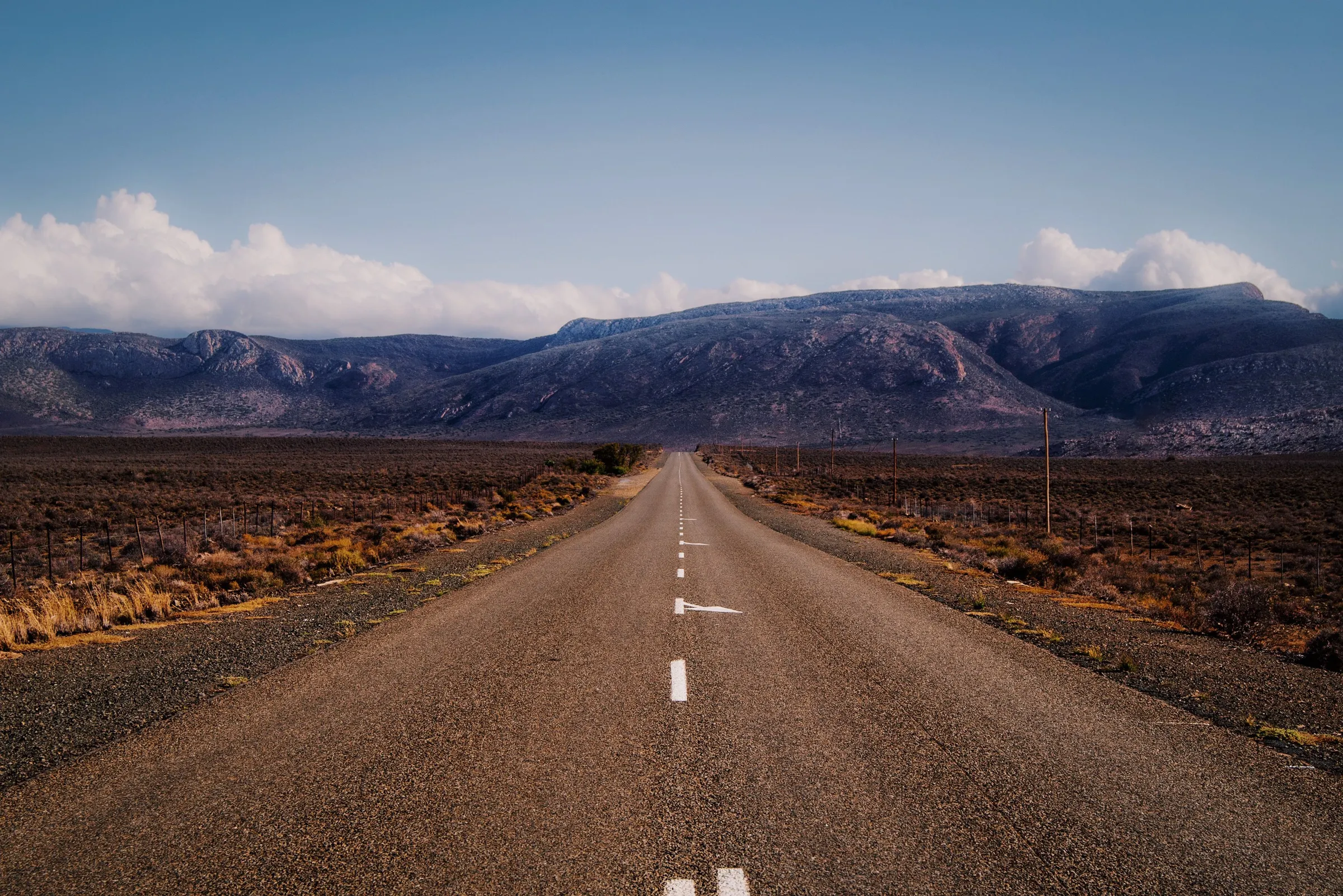 A straight road across a flat plain towards a mountain range