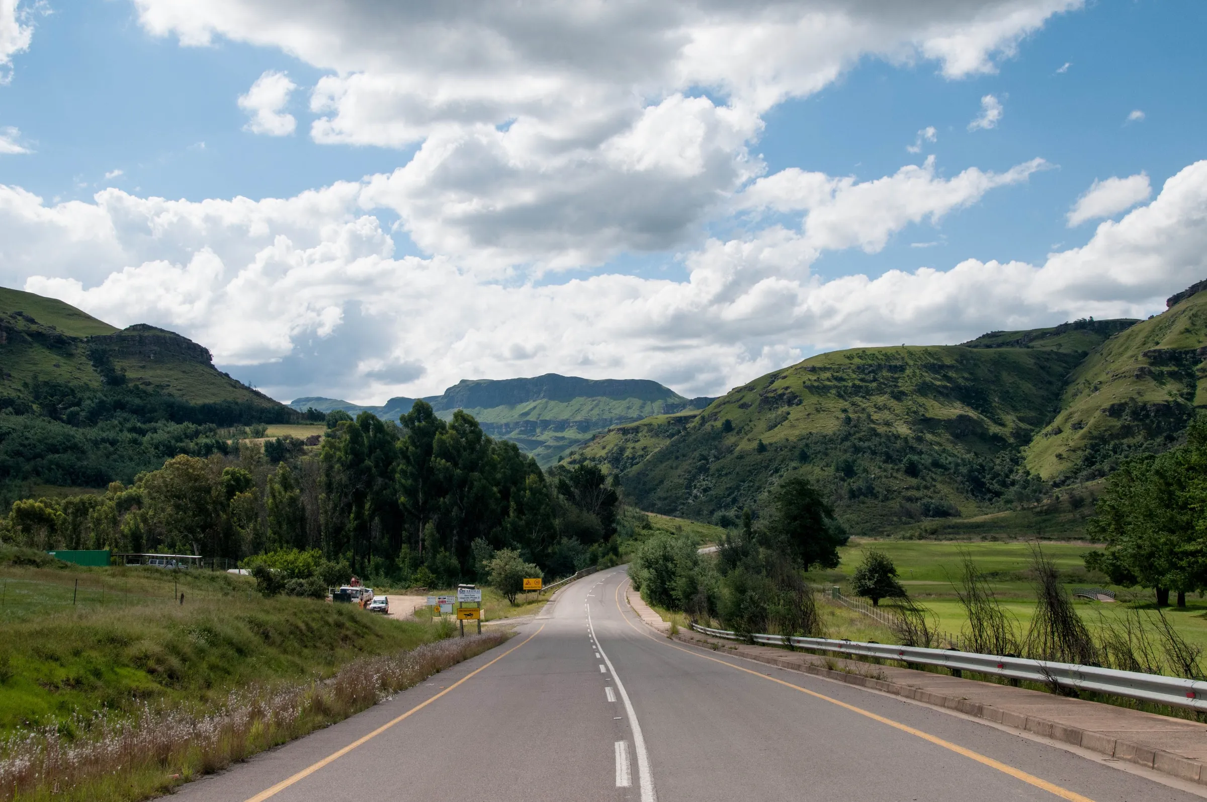 A two-lane road through green valleys and hills